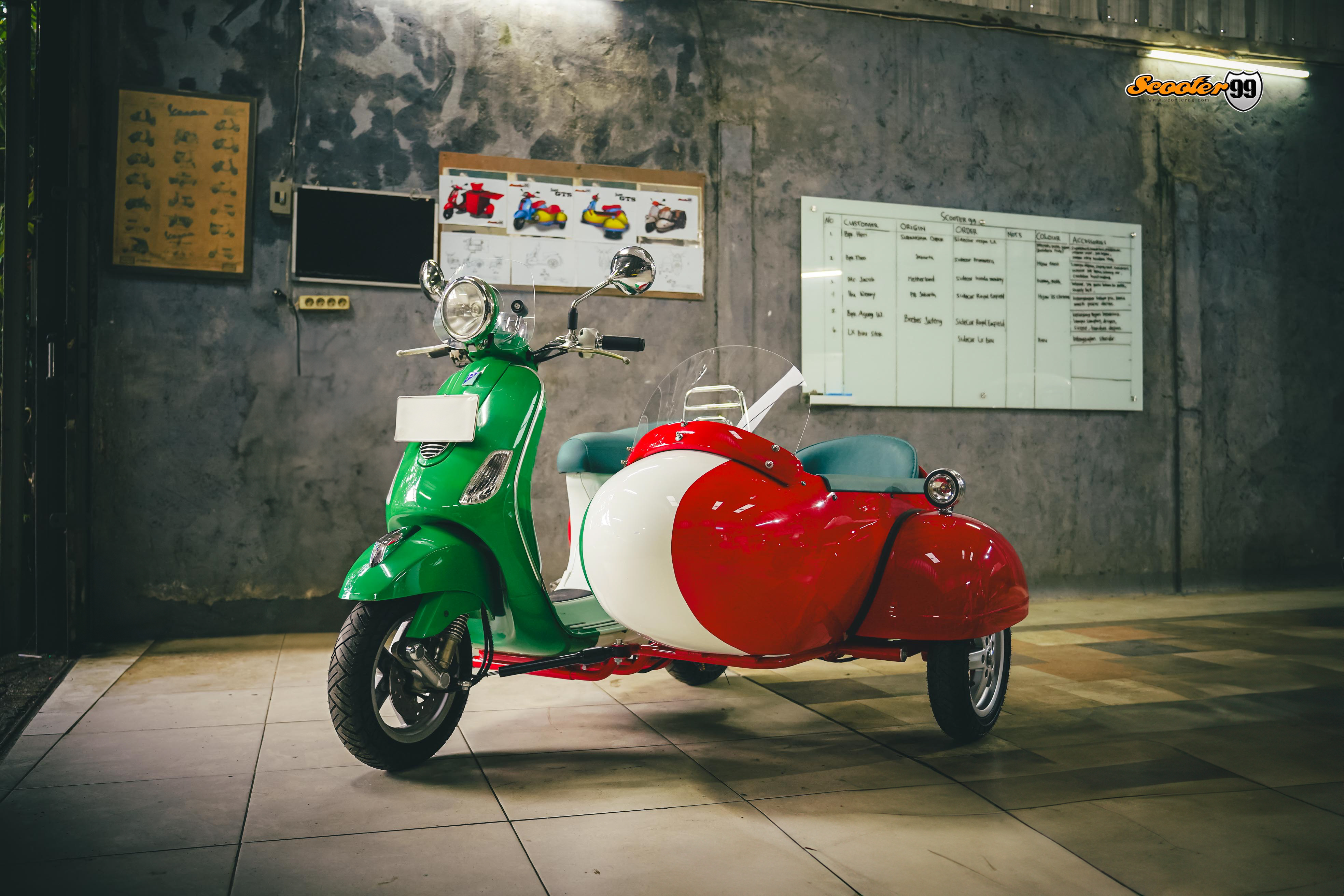 Custom Vespa with Italian flag livery and matching sidecar inside the Scooter99 workshop.